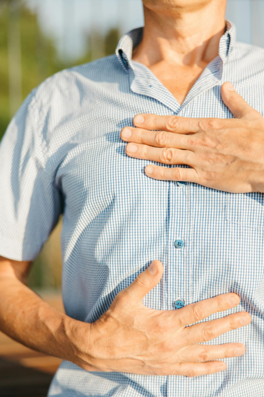 man holding chest with heartburn pain sitting on couch